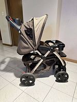 Side view of the stroller showing the frame, wheels, fabric seat, canopy, and storage basket.