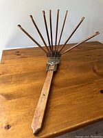 Front view of vintage wooden wall-mount clothes drying rack with 8 arms fanned out, sitting on wooden table.
