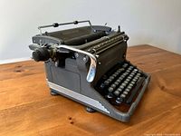 Left side angled view of grey Underwood manual typewriter showing keyboard, platen knobs, and metallic details.