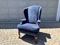 Front view of blue wingback armchair showing upholstery and wooden legs.