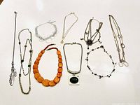 All 9 costume jewelry pieces including necklaces and a bracelet laid out on white background.