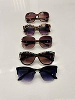 Top view showing all five pairs of sunglasses arranged in a row, visually displaying variety in frame shapes and lens colors.