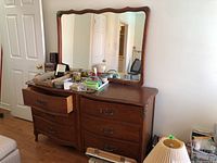 Wide shot showing the full dresser with attached mirror, one drawer open and various items on top