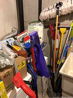 General overview of assorted cleaning items including vacuum, brooms, mop, cleaning wipes and dustpan brush