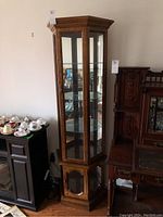 Full view of wooden curio cabinet with glass doors, glass shelves, and bottom compartment.