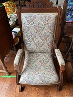 Angled view of Eastlake rocking chair highlighting woodwork and upholstery including seat stains.