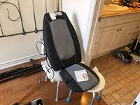 Shiatsu massaging cushion on white tub stool near black tub chair