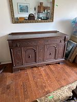 Front view of full sideboard showing dark hardwood, two doors below and single upper drawer with brass pulls and carved detailing