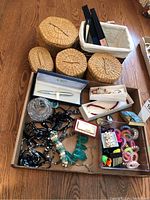 Photo of baskets, jewelry, pen, lighter and fans laid out on wooden floor