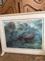 Framed limited edition print depicting manatees underwater in blue and green tones