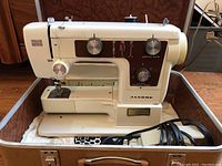 Janome portable sewing machine in cream and brown, showing side and control knobs with stitch patterns and dials.