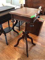 Side angle view of antique wooden side table showing curved legs and pedestal base