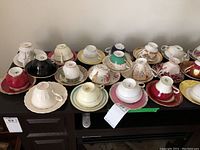Wide view displaying 22 assorted teacups and matching saucers featuring various vintage patterns and colors from brands such as Paragon, Spode, Adderley, Aynsley
