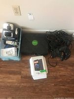 Original Xbox console with 4 controllers and various cables and small electronics on floor.
