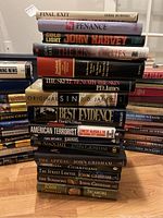 Stack of hardcover books showing multiple authors including John Grisham, P.D. James, John Harvey, and others.
