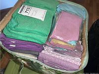 Top view of a bag containing folded green, purple, pink waffle weave, and other assorted cleaning towels.