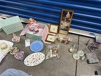 Overview of all items included in the lot, showing Madame Alexander doll, ceramic dishes, small wall hangings, tea light holders, and geode pieces on the floor.