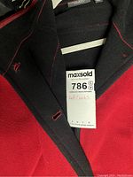 Close-up of red coat with black collar showing auction tag labeled 'Red Coats'