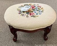 Front view showing foot stool overall shape, legs, and embroidery.