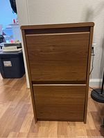 Front view of wooden filing cabinet showing two large drawers with flush fronts and brown wood grain finish.