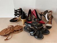 Full view of eight pairs of women's summer shoes including black leather Balenciaga sandals, red heels, black heels, and tan flat sandals