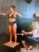 Photo of woman receiving a spray tan treatment indoors, illustrating the service offered.