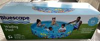Photo of the boxed Bluescape inflatable wading pool showing the packaging with a picture of children playing in the blue, aquatic-themed pool and label indicating 8 ft diameter.