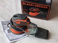 Black & Decker 5-inch random orbit sander with original box, instruction manual, and dust collection bag visible.