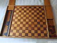Full view of large wooden checkers board with both sliding compartments open showing black and red checkers pieces inside.