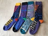Four pairs of colorful PHILOSOKPHY men's dress socks laid flat showing full length and pattern details.
