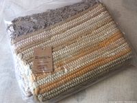 Photo of the packaged hand woven cotton rug showing beige, cream, yellow striped pattern with fringe edge and Rivancia tag.