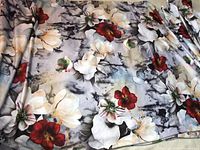 Photo showing floral fabric with white and red flowers on gray and black background, folded and spread out.