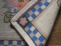Close-up of corner showing blue and beige checkered border and fabric edge backing.