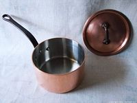 Side view of copper pot with lid removed showing tin-lined interior and iron handle