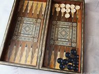 Open board showing interior backgammon playing surface with geometric inlay and dark and light round checkers
