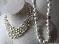 Full view of the two pearl necklaces displayed on a neutral mannequin, showing the multistrand choker and single strand necklace draped over shoulder.