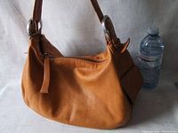 Front view of the vintage cognac soft leather COCCINELLE shoulder bag showing front zipper, strap, and soft textured leather.