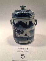 Front view of the blue and white ceramic soup pot or tea caddy with lid in place showing landscape design