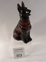 Front view of the dark brown and black glass German Shepherd shaped Avon bottle, showing detailed fur texture and sitting pose.