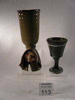 Front view of both handmade ceramic wine goblets showing sculpted face detail on taller goblet and simpler smaller goblet.