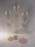 Three Jon Art luxury champagne flutes with colored accents and clear glass showing details of design and measurements.