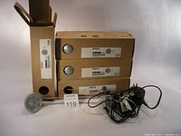 Four IKEA Gruva lights stacked in boxes with power cords and one light outside the box showing lamp head and arm.