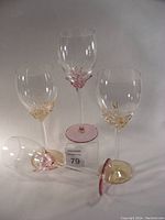 Four Jon Art luxury wine glasses showing two with pink and two with gold decorative stems and bases.