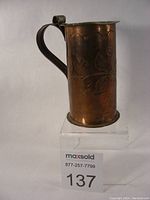 Overall side view of copper Arts & Crafts handled pitcher placed upright showing engraved floral pattern.