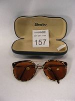 Top view of tortoise shell sunglasses and the Sferoflex case with cream interior lining and branding