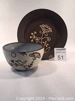 Image showing black clay bowl with bird and floral decoration and matching saucer with floral design.