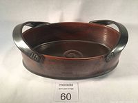 Front angled view showing brown glazed ceramic surface and metal handles with rivets.