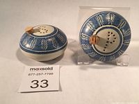 Pair of round blue and white pottery salt and pepper shakers with cork stoppers and leaf pattern