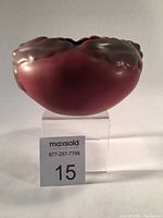 Front angle of burgundy matte pottery vase showing rounded shape and raised oak leaf and acorn motif details.