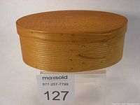 Closed view of oval shaker style bentwood box, showing smooth natural wood finish and copper tacks on the bentwood sides.